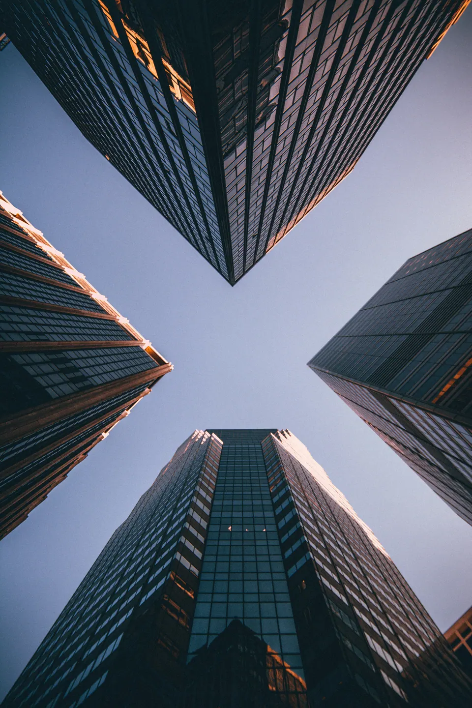 Upward view of modern glass office towers framing the sky