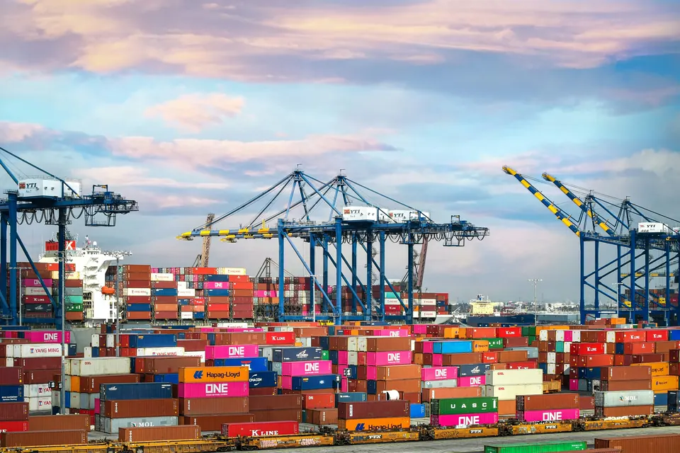 Container shipping terminal with cargo cranes, stacked containers and a ship
